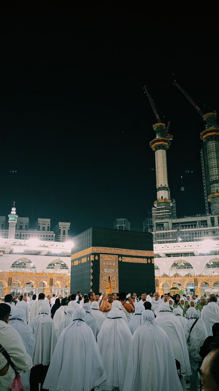 A group of pilgrims gathers at the Kaaba in Mecca during a night-time visit, capturing the spiritual essence of the holy site.